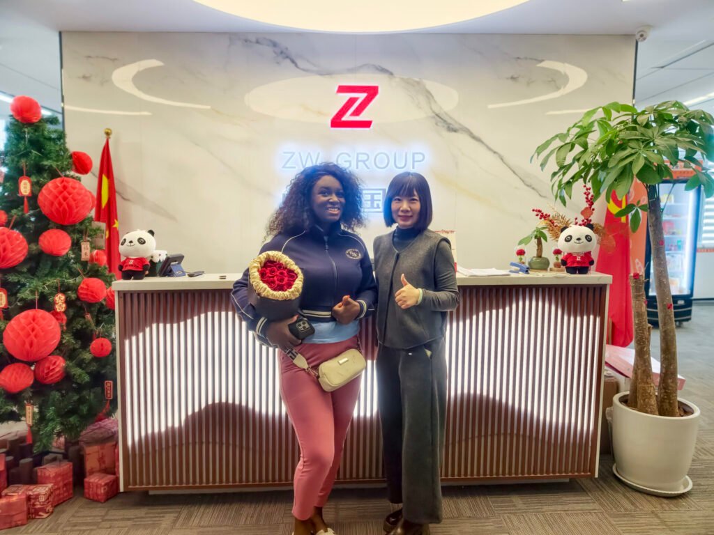 Cindy with Ghana client taking a photo at the entrance of ZW Group factory after confirming flatbed semi trailer order